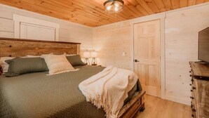 Un dormitorio con paneles de madera, una cama, lámparas de noche y un aparador.