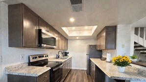 Una cocina moderna con armarios oscuros, un microondas, estufa y un tragaluz.