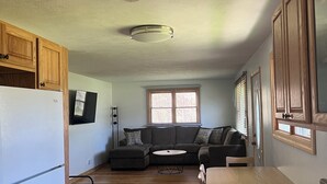A compact living space with a kitchenette, a sofa, and a dining area. - M-28 House
Direct Trail Access - Ample Trailer Parking - Year-Round Fun (Marquette)