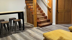 A wooden staircase with a handrail, a wooden door, and a yellow upholstered sofa. - M-28 House
Direct Trail Access - Ample Trailer Parking - Year-Round Fun (Marquette)