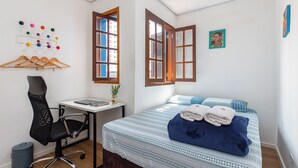 Un dormitorio con cama, escritorio, silla y ventana.