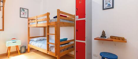 A bunk bed room with a red storage unit and a small desk with a chair.