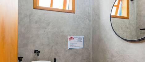 A bathroom with a white sink, toilet, and a window with a wooden frame.