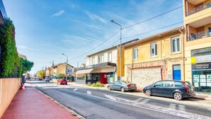 A street with buildings, a red fire hydrant, and cars parked along the road. - La Suite Soleil - Maison studio avec jardin privé (Décines-Charpieu)