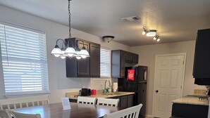 A modern kitchen with a dining table, white chairs, and a built-in oven. - Rustic Wheel-horse House. Entire one-level 3/2 home located in Granbury, TX. (Granbury)