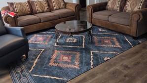 A living room with two brown sofas, a glass coffee table, and a patterned rug. - Rustic Wheel-horse House. Entire one-level 3/2 home located in Granbury, TX. (Granbury)