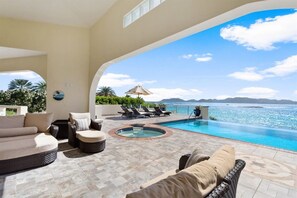 A pool area with lounge chairs and a hot tub, overlooking a clear blue sea and distant mountains. - Dolphin at Anguillitta: 3BR Beachfront, Book Now! (Blowing Point)