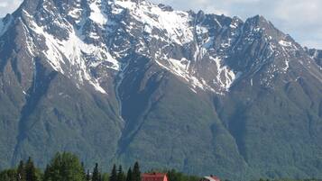 Un paysage de montagne avec une grange et une petite maison au premier plan.