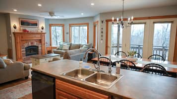 A kitchen with a fireplace, dining area, and a large window.