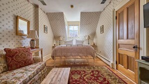 Un dormitorio con cama, sofá, banco de madera, ventana y puerta.