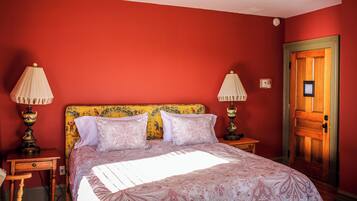 Una habitación con una cama, dos lámparas de noche, una puerta de madera y una mesita.