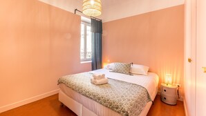 A bedroom with a bed, a bedside lamp, and a window with curtains.