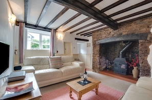 A cozy living room with a stone fireplace, a white sofa, and a wooden coffee table. - A charming, pet-friendly 2 bedroom cottage (Braunton)
