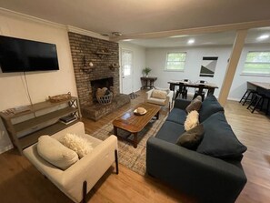 Un salón con chimenea, sofá, mesa de centro y televisor.