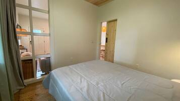 A bedroom with a large bed, a wooden ceiling, and a sliding door leading to a bathroom.