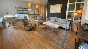 Un salon moderne comprenant un canapé, des fauteuils, une table basse et un coin repas avec une table et des chaises.