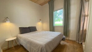 Une chambre à coucher avec un lit, une petite table et une fenêtre avec des rideaux.