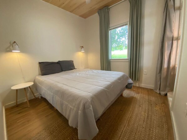 Ein Schlafzimmer mit einem Bett, einem kleinen Tisch und einem Fenster mit Vorhängen.