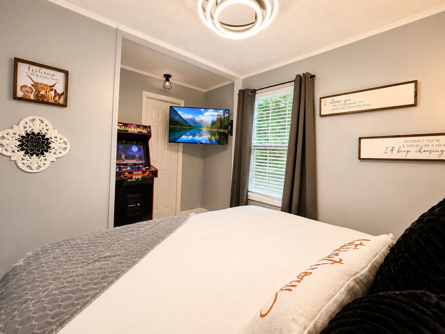 Une chambre à coucher comprenant un lit, un téléviseur, une horloge murale et une porte donnant sur une autre pièce.