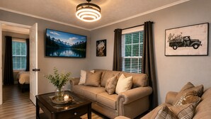 A living room with a sofa, a coffee table, and a painting of a mountain landscape.