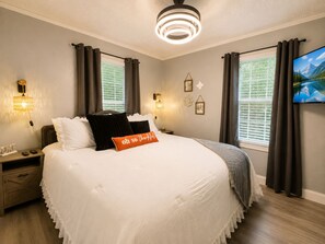 Ein Hotelzimmer mit einem großen Bett, zwei Nachttischen, einem am Wand montierten Fernseher und einer Deckenleuchte.