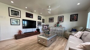 Una sala de estar moderna con un televisor de pantalla plana, un ventilador de techo y un sofá.
