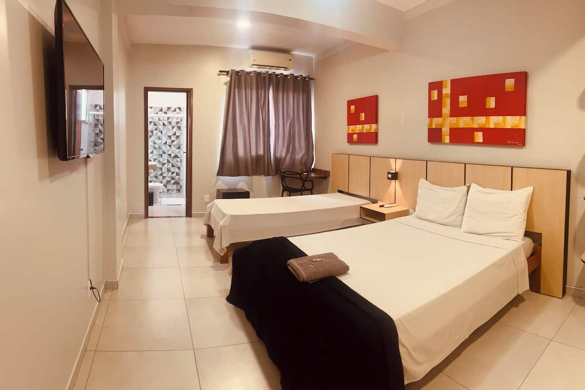 A hotel room with two beds, a TV, a desk, and a wardrobe.