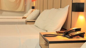 Una camera d'albergo con un letto, un comodino con il telefono e uno squadrato.