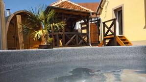 Una piscina amb una vores de pedra, un pont d'obra i una palmera petita.
