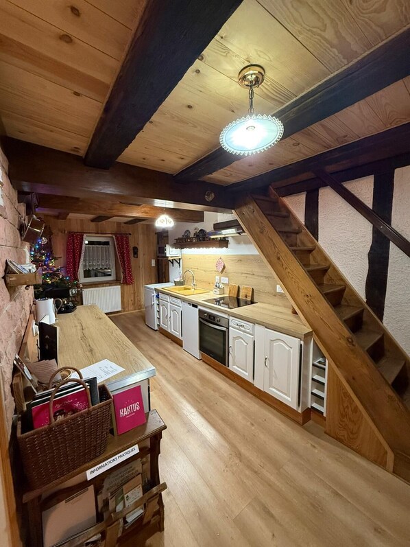 Une cuisine chaleureuse avec des poutres en bois, un escalier et un sapin de Noël décoré pour les fêtes.