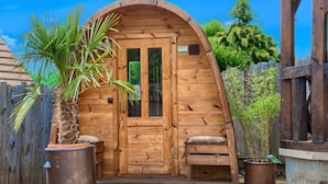 Una cabana de fusta amb teulada corba, una porta d'entrada i una petita banca.