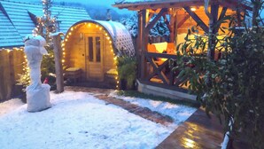 Una cabana de fusta acollidora amb un teulat cobert de neu, un interior amb llum càlida i el terra ple de neu.