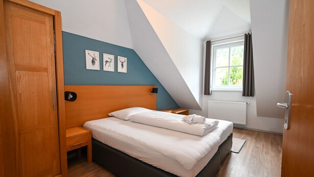 A bedroom with a bed, wooden wardrobe, and a window with curtains. - Kitz Residenz Twelve View of the River (Kaprun)