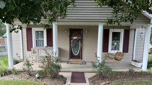 A house with a front porch, a decorative door, and a small garden area.