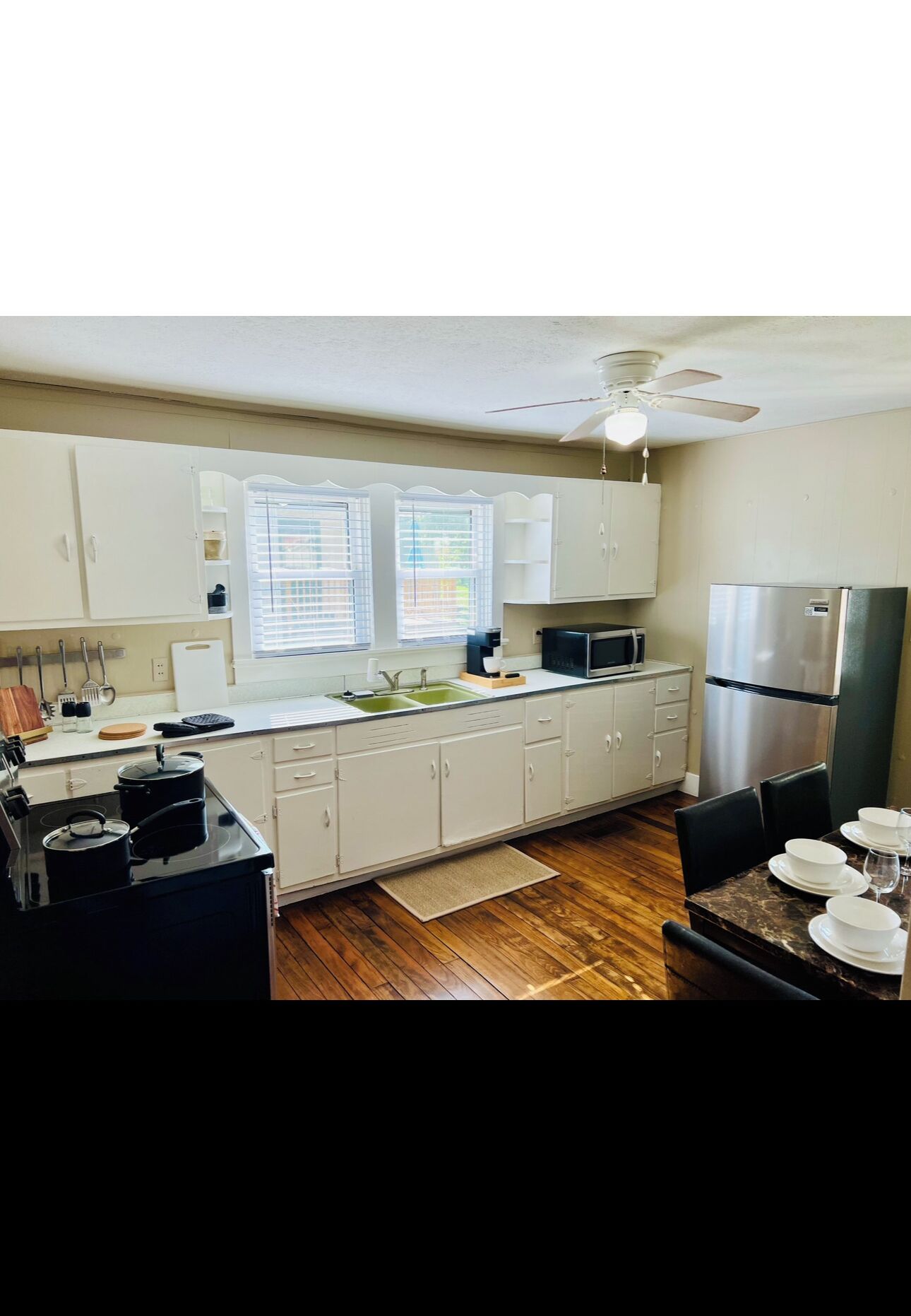 A modern kitchen with white cabinets, a stainless steel refrigerator, a microwave, and a gas stove.