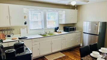 A modern kitchen with white cabinets, a stainless steel refrigerator, a microwave, and a gas stove.