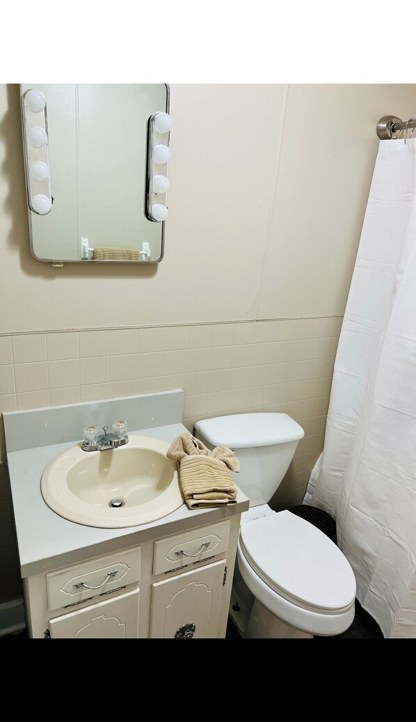 Un baño con lavabo, espejo e inodoro.