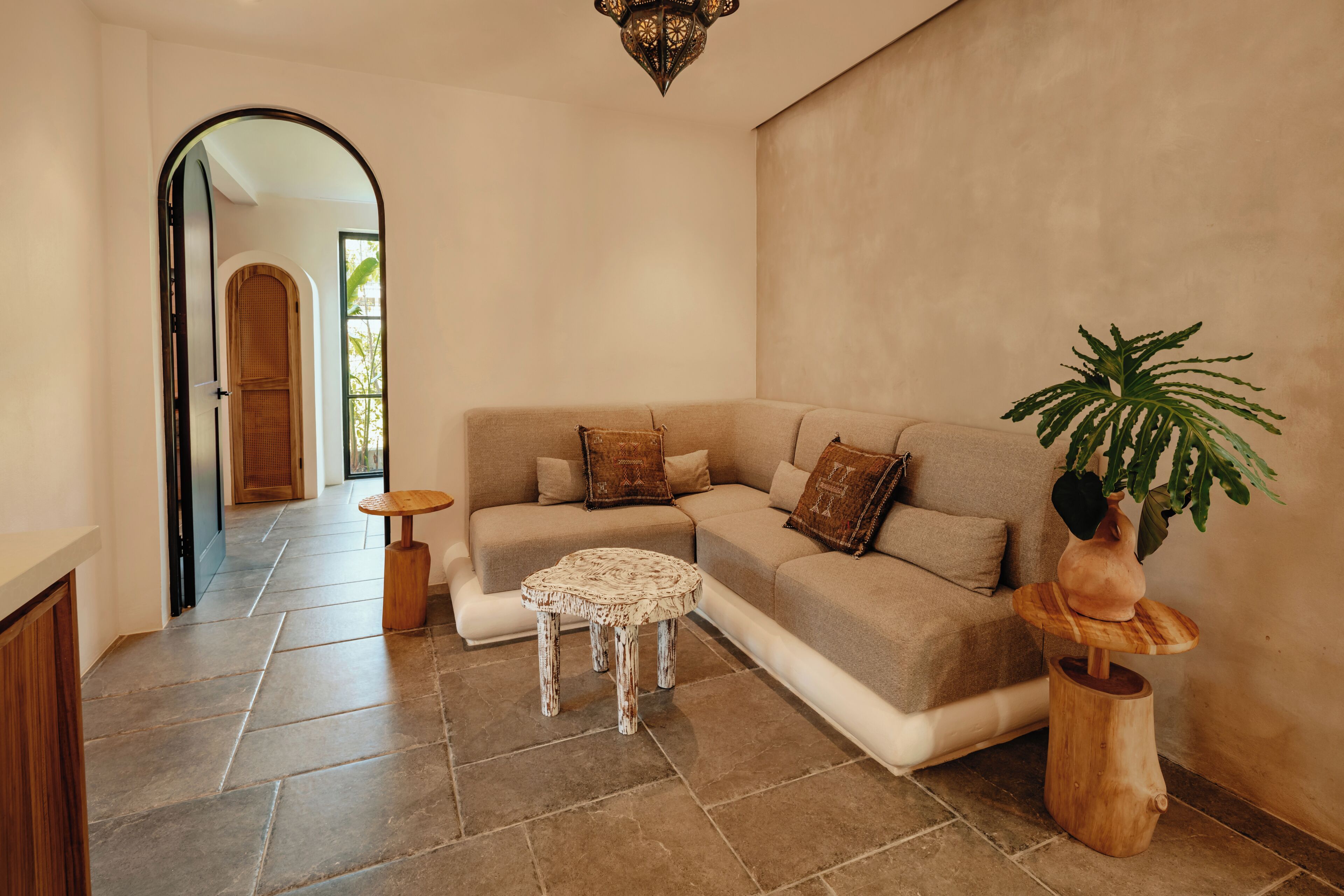 A modern living room with a sectional sofa, a small round table, and a potted plant.