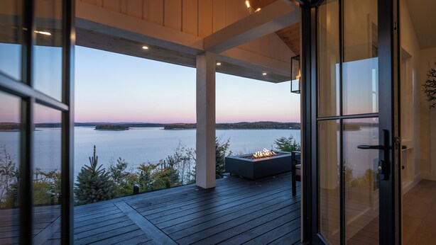 A deck with a fire feature, overlooking a body of water and distant land.
