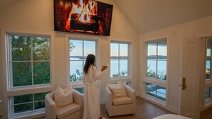 A spacious room with large windows overlooking a body of water, a fireplace, and a comfortable seating area.