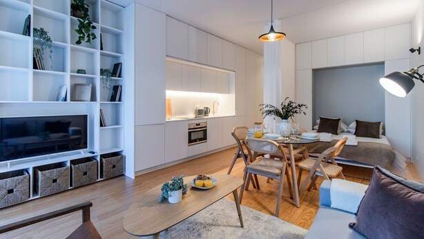 A modern living room with a TV, bookshelf, dining area, and a sofa.