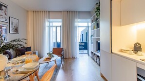 A modern living room with a dining area, large windows, and a view of the city.
