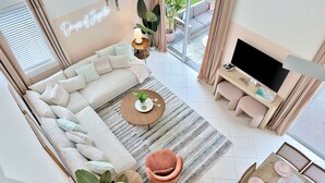 Uma sala de estar moderna com sofá, mesa de centro, TV e um letreiro neon.
