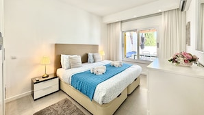 A modern bedroom with a large bed, bedside tables, a nightstand, and a view of the outdoors.
