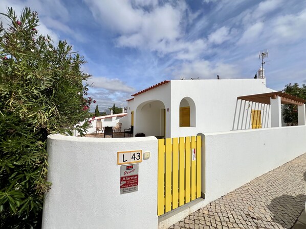 Un bâtiment blanc avec un portail jaune portant l’inscription « L 43 » et un panneau indiquant la présence d’un service de sécurité.