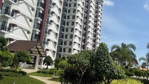 A high-rise residential building with multiple balconies, a landscaped garden area, and a clear sky. - Transparent hosting devoid of excessive fees and stress-free check-in procedures (Lapu-Lapu City)
