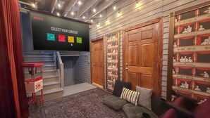 Een gezellige kamer met een Netflix scherm, een kamerbreed tapijt, een bank en een boekenkast met decoratieve objecten.
