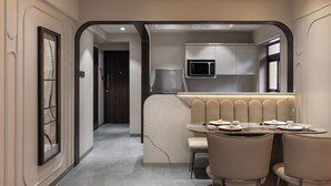 Un espace repas moderne agrémenté d’un mur d’accent en marbre, d’un micro-ondes encastré et d’un coin salon avec des chaises rembourrées.