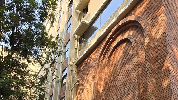 Un bâtiment à la façade en briques, doté de grandes fenêtres et d’une cour spacieuse.