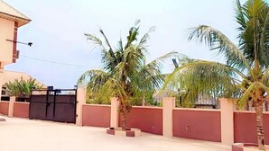 A residential area with a gated entrance, palm trees, and a parked car.